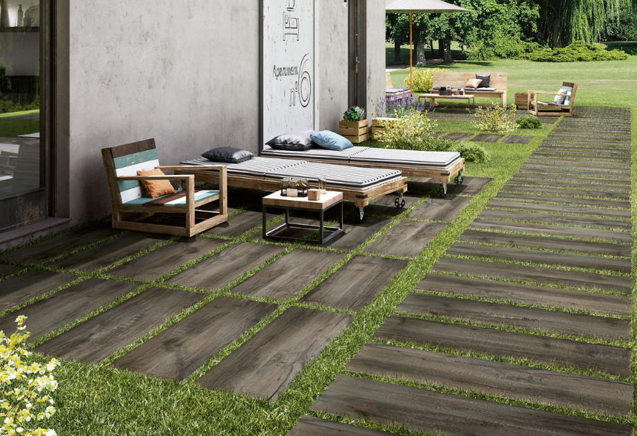 outdoor patio area with faux wood porcelain pavers in the grass with furniture on top